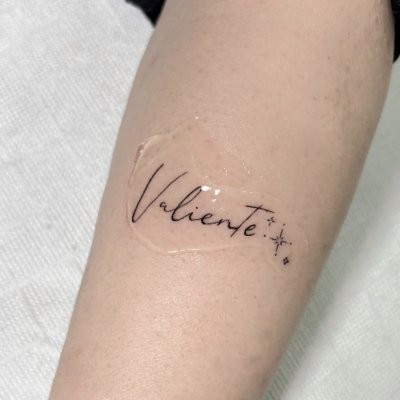 Lettering fine line — tatuaje Valiente con estrellas en el antebrazo