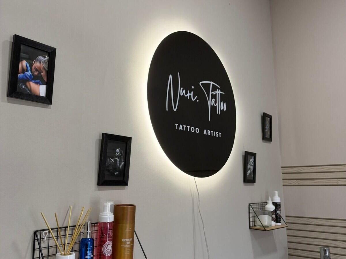 Logotipo iluminado Nuri.tattoo en el interior del estudio